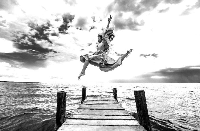 a woman is jumping off a dock into the water